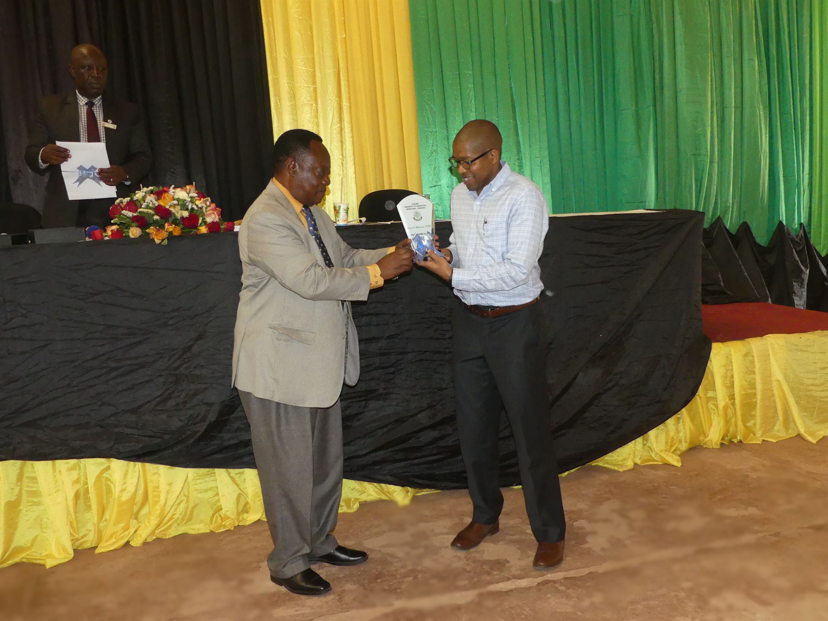 Founder and Managing Director of Shambani Graduates Enterprises Limited Mr. Victor Mfinanga (right) receiving a distinguished SUA alumni award from president of Sokoine University of Agriculture Convocation Prof. Ruwa-Aichi P.C Temu