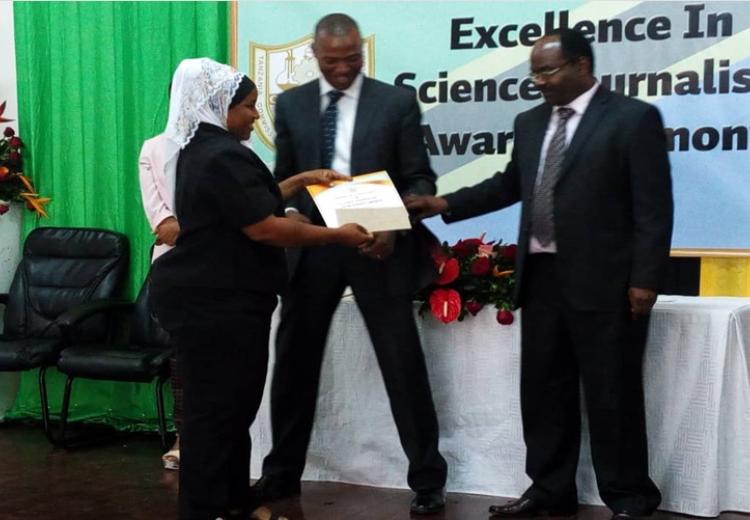 SUAMEDIA correspondent Farida Mkongwe (left) receiving prizes on behalf of Calvin Gwabara of SUAMEDIA from the permanent secretary in the Ministry of Education, Science and Technology Dr. Leornad Akwilapo(Right). Witnessing is the acting Director General of the Tanzania Commission for Science and Technology (COSTECH) Dr. Amos Nungu