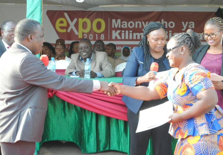 Josephine Mallango SUAMEDIA journalist shaking hand with the Minister for Agriculture Dr. Charles Tizeba after receiving the First Winner's award on television on behalf of Mr. Calvin Edward Gwabara in Arusha Tanzania.