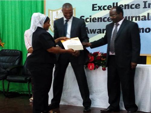 SUAMEDIA correspondent Farida Mkongwe (left) receiving prizes on behalf of Calvin Gwabara of SUAMEDIA from the permanent secretary in the Ministry of Education, Science and Technology Dr. Leornad Akwilapo(Right). Witnessing is the acting Director General of the Tanzania Commission for Science and Technology (COSTECH) Dr. Amos Nungu