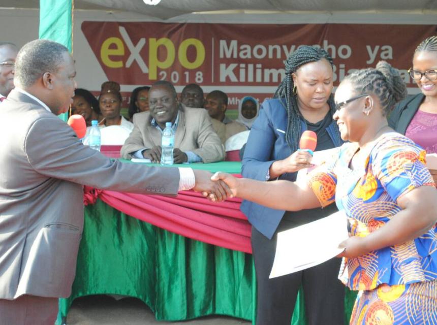 Josephine Mallango SUAMEDIA journalist shaking hand with the Minister for Agriculture Dr. Charles Tizeba after receiving the First Winner's award on television on behalf of Mr. Calvin Edward Gwabara in Arusha Tanzania.